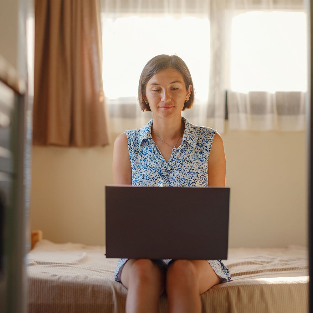 woman on laptop on bed